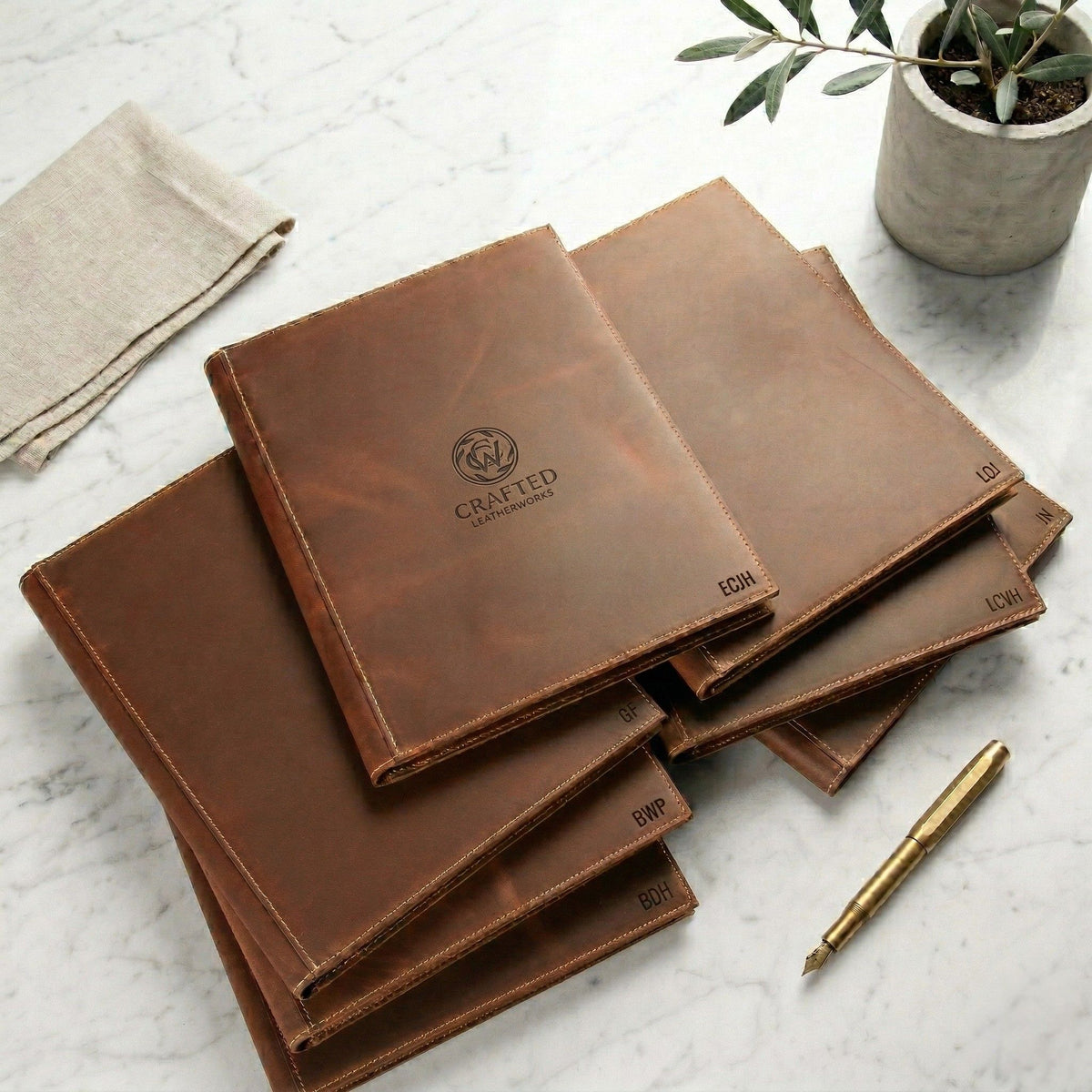 Personalized brown leather journals and business gifts arranged on a desk